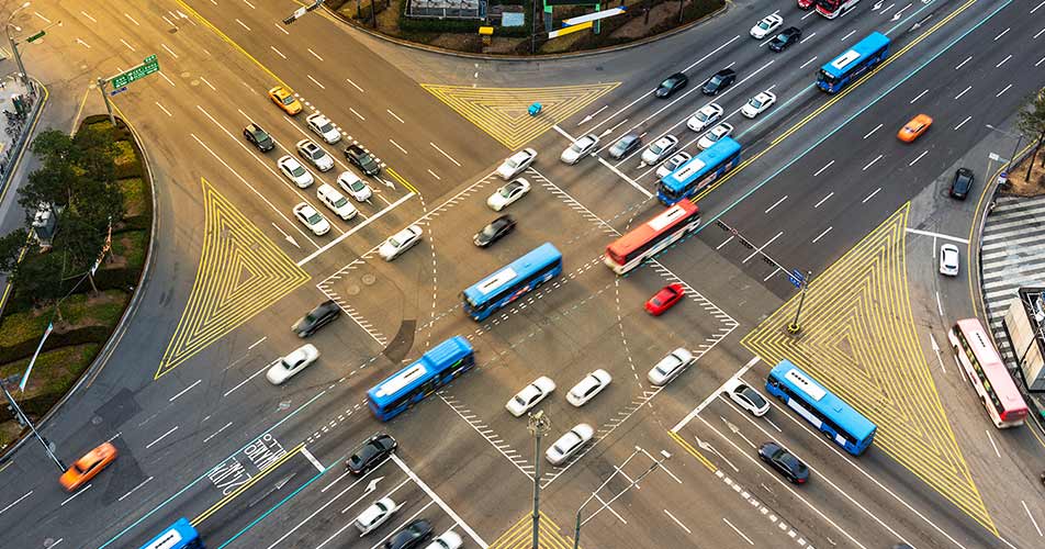 A bird's-eye view of a busy city intersection, with traffic crossing, while others wait, illustrating Huawei FTTM for highways
