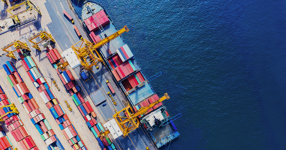 Seen from above, a container ship docked at port with cranes loading cargo containers, illustrating Huawei FTTM for ports